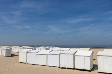 White beach houses in a row in the sand on the North Sea coast in Belgium on a sunny day with blue sky