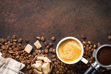 Cup of coffee, roasted coffee beans and filter holder at dark table.