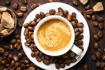 Cup of coffee, roasted coffee beans and filter holder at dark table.