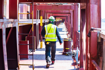 A port employee, stevedore,  walking across the deck of a merchant ship during his daily routine...