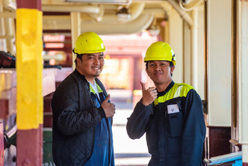 Happy, smiling sailors on a merchant ship, dressed in protective gear and yellow helmets.