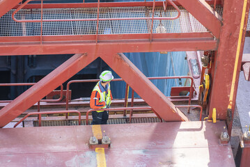 A port employee, stevedore, standing on deck of a container ship during his daily routine activities on board of merchant vessel.