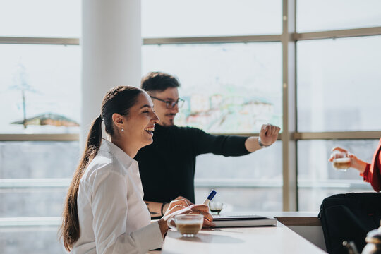 Business employees enjoying a lively moment in a modern office kitchen. They are smiling, engaging, and fostering a positive work environment, reflecting teamwork and employee well-being.