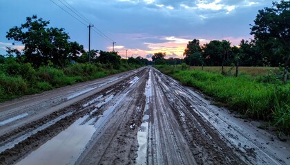 Obraz premium Muddy Rural Road at Sunset with Dramatic Sky and Greenery