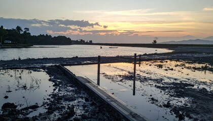 Fototapeta premium Serene Sunset Reflection Over Calm Water by Sandy Shoreline