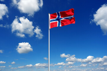 flag of Norway fluttering in the blue sky with cumulus clouds