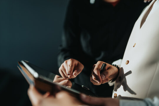 Close-up of business people collaborating and discussing strategies using a digital tablet. Teamwork and technology drive their productivity in a modern office setting.