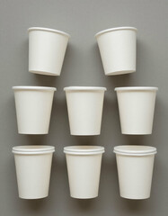 White Paper Cups Arranged on Grey Wall Background

