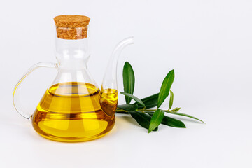Glass olive oil cruet with olive branch on clean white background