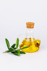 Healthy olive oil in glass bottle with fresh branch on white backdrop