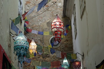 colorful lanpions and little flags in front of the brick wall of an alley