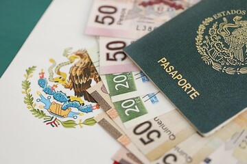 Mexican pesos money bills in big amount and passport lies on Mexico flag close up