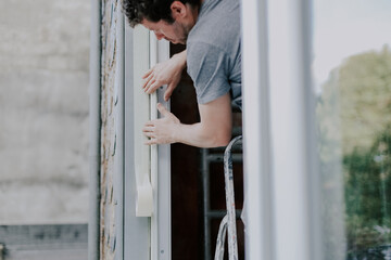One young worker repairs window frames by gluing on tape.
