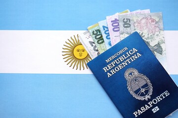 Argentine pesos money bills in big amount and passport lies on Argentina flag close up
