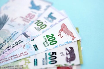 Argentine pesos money bills in big amount lies on teal color table close up