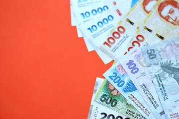 Argentine pesos money bills in big amount lies on red color table close up