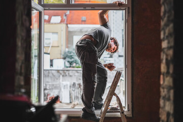 A young worker inspects window frames before repairs.