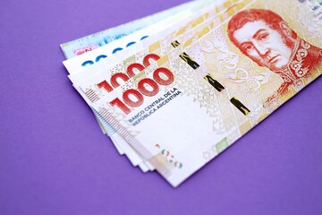 Argentine pesos money bills in big amount lies on purple color table close up