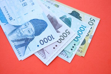 South Korean won money bills in big amount lies on red color table close up