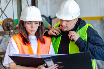 Female engineer holding and showing a binder to a male worker at construction site. Engineer concept