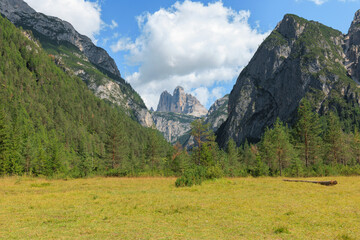 Majestic Tre Cime di Lavaredo towers over lush greenery in the Dolomites. Clear skies and rugged mountains invite outdoor enthusiasts to explore the breathtaking landscape.