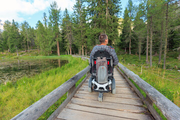 Person using wheelchair navigates accessible trails in the Dolomites surrounded by lush greenery in...