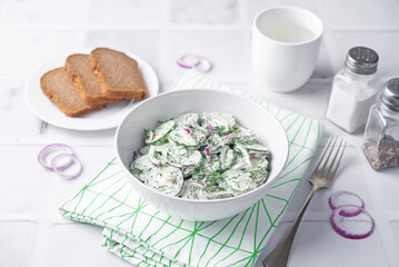 Cucumber red onion dill salad in a bowl on a white background