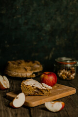 Traditional apple pie Charlotte apples are lying nearby. Sweet Thanksgiving dinner, autumn seasonal apple pie sliced one piece on wooden tray, on dark wooden background.