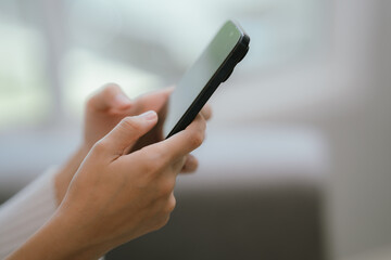 Close-up of a young woman's hand holding a smartphone and chatting on social media.