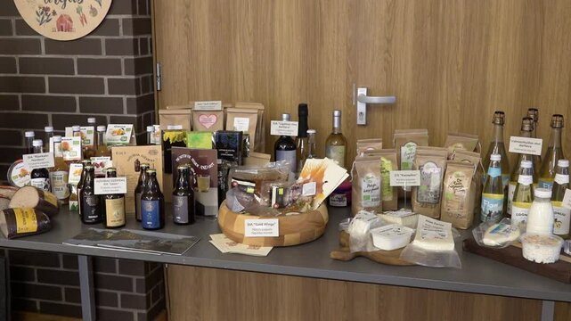 Display table with a variety of Latvian organic food products, including bread, drinks, cheese, grains, and juices at a local bio market.
