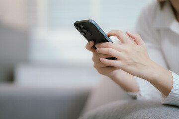 Close-up of a young woman's hand holding a smartphone and chatting on social media.