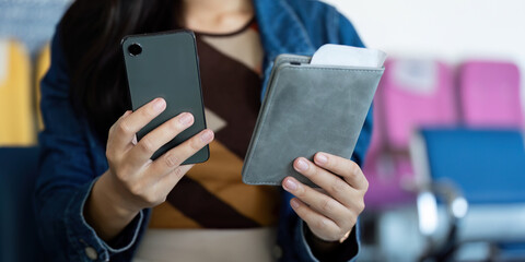 Journey preparation with traveler holding smartphone and wallet at airport