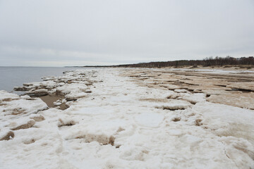 This picturesque scene features a snowy beach complemented by a beautiful body of water visible in the background, creating a serene winter backdrop