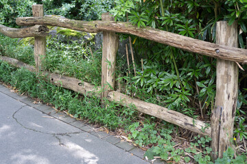 Fototapeta premium Old weather-worn wooden log fence in a summer rural area