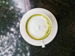 Top view hot matcha green tea latte on black marble table.
