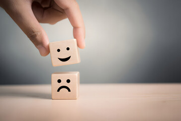 Choosing happiness over sadness illustrated with wooden blocks and a hand gesture