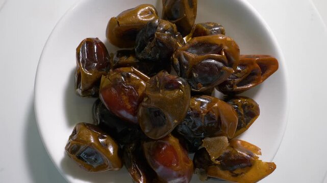 Dried dates in a top view plate. On a turntable, it spins in motion. Slow motion.