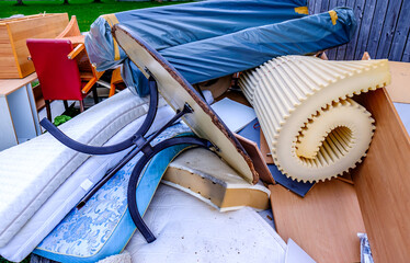 Discarded furniture and debris cluttering a vacant lot in an urban area during daylight hours