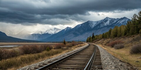 Fototapeta premium Railway Tracks Winding Through Autumnal Landscape Towards Snowy Mountains