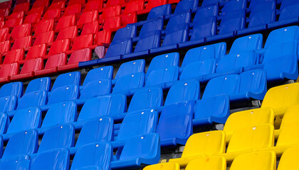 Naklejka premium Rows of vibrant stadium seating, red, blue and yellow. Conveys unity, team spirit, and the anticipation of a crowd. Perfect for sports, events, or abstract backgrounds.