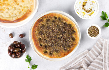 Flatbread Manakish with cheese and zaatar, olives, labneh on white background. Copy space. Top view.