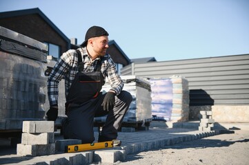 Construction worker installing and laying pavement stones on terrace, road or sidewalk. Worker...