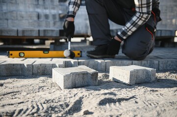 The master in gloves lays paving stones in layers. Garden brick pathway paving by professional...