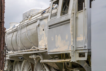Close-up of a vintage steam locomotive undergoing restoration, covered with a layer of primer paint. Visible structural details, wheels, and part of the driver's cab. Perfect image for themes of railw