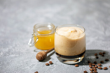 Honey Dalgona Coffee. Whipped instant vegan coffee in a glass with beans . Concept of a trendy and popular drink.