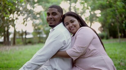 Happy biracial couple embracing in lush green park
