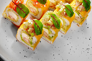 Delicious sushi rolls with omelette, shrimp, avocado, and tobiko on a plate