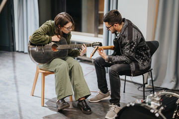 Two individuals working together in a studio setting, playing an acoustic guitar during a collaborative music session, emphasizing teamwork, learning, and the creation of music.