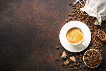 Cup of coffee, roasted coffee beans and filter holder at dark table.