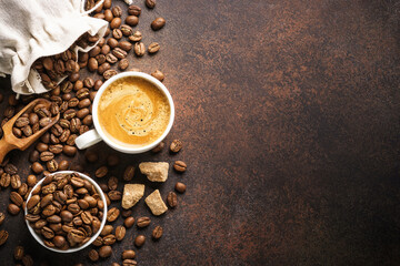 Cup of coffee, roasted coffee beans and filter holder at dark table.